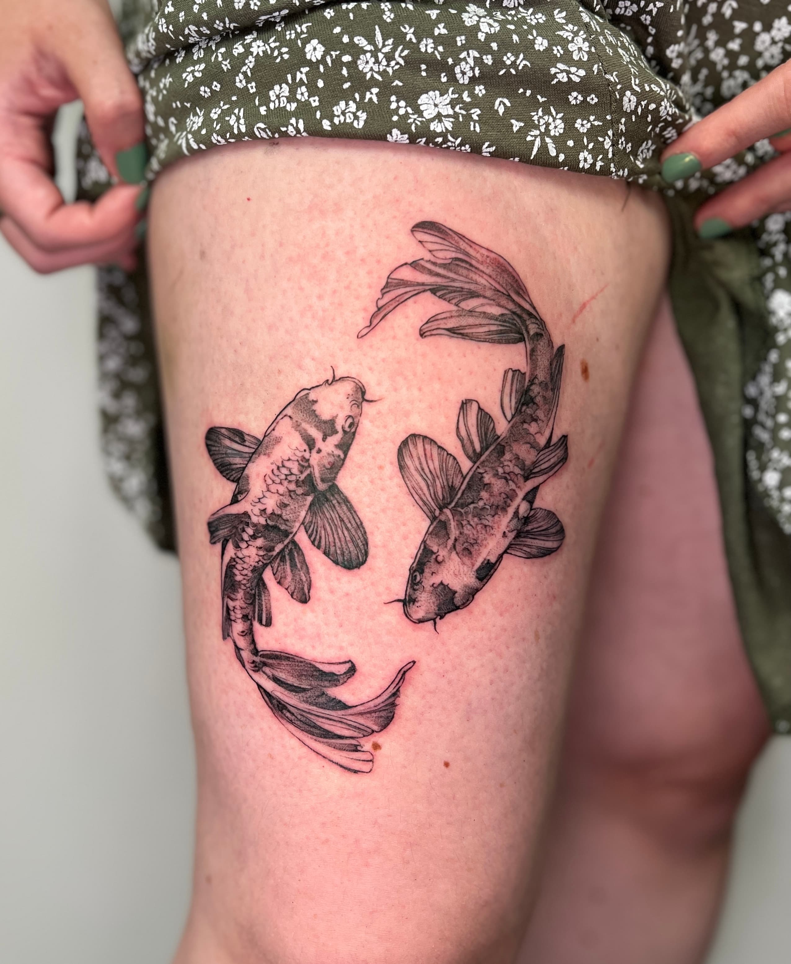 Detailreiches fineline Tattoo von zwei Koi Fischen in ovaler Komposition am Oberschenkel